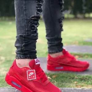 Tenis deportivos Air Max rojos para caballero, con malla transpirable, suela con amortiguación visible y etiqueta de marca, usados en entorno urbano.